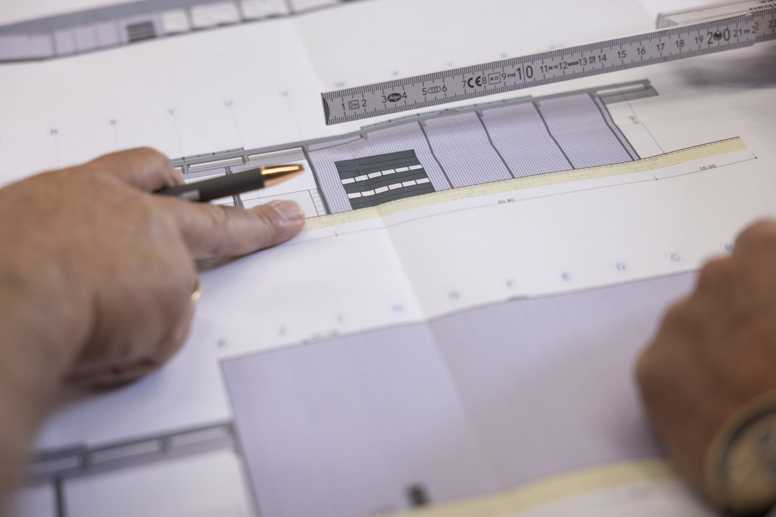 Bauplan Eine Person zeigt mit dem Finger auf einen Bauplan